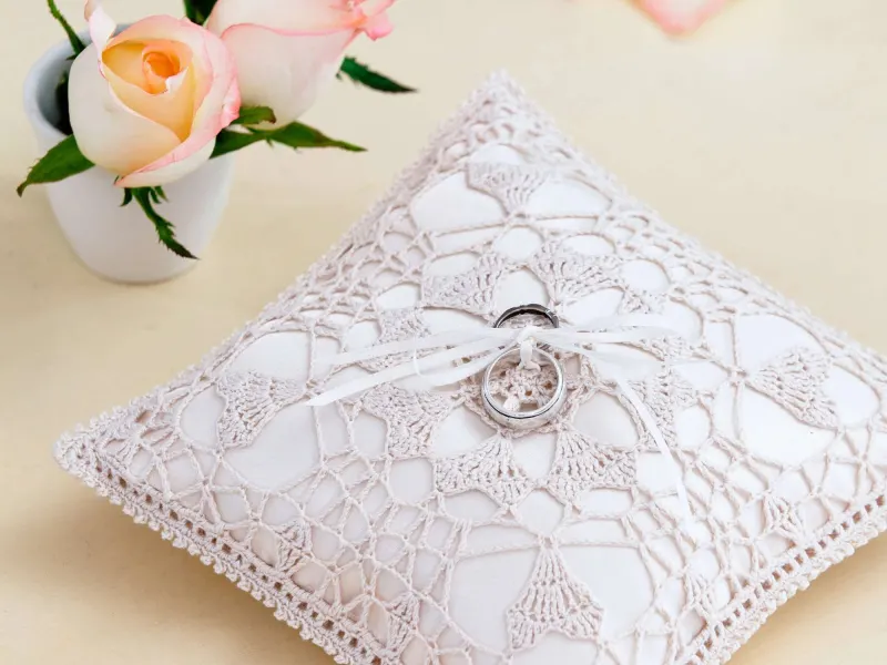 White thread crochet pillow with heart motifs and satin ribbon