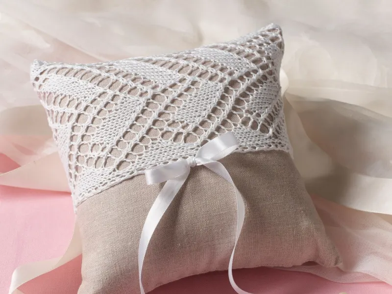 Delicate white thread crochet ring pillow with lace edging