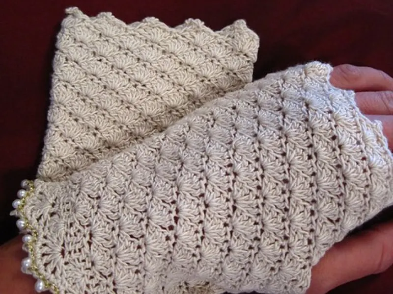 White shell-stitch crochet fingerless mitts on a hand