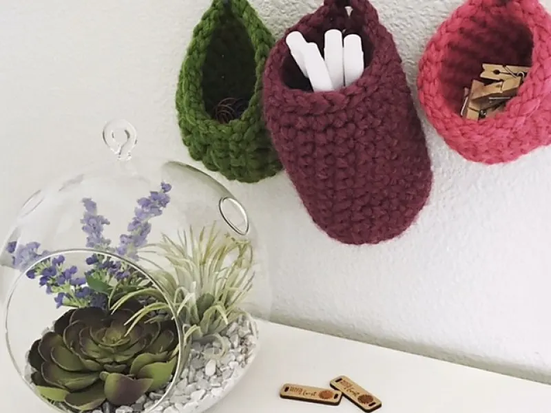 Three chunky crochet baskets hanging together on a wall