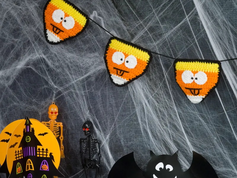 Crochet candy corn banner hanging in orange, yellow and white