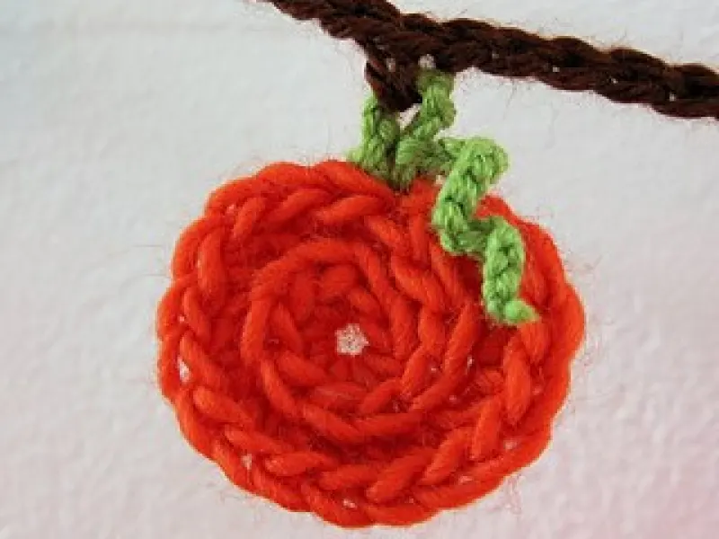 Row of small orange crochet pumpkins on a string