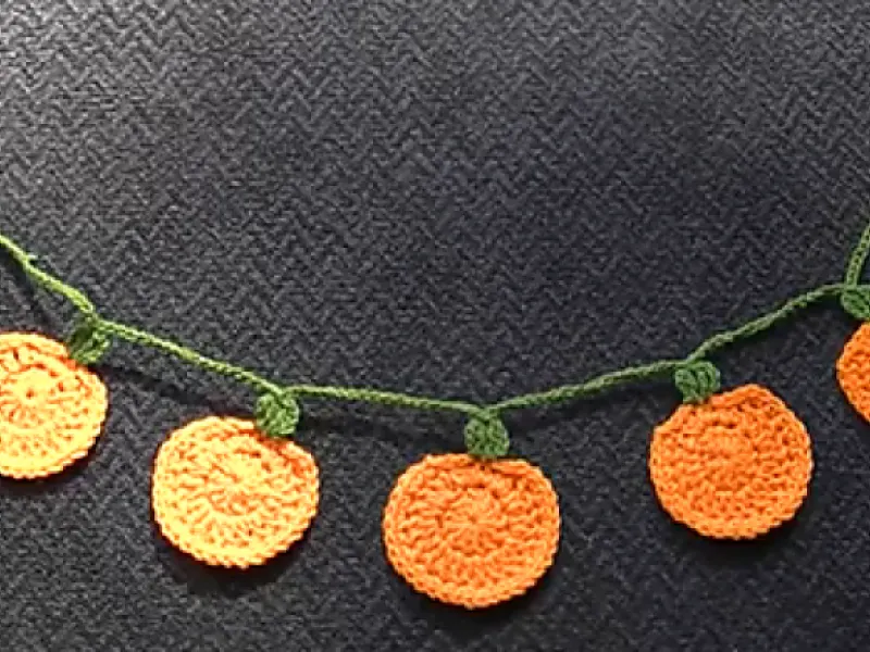 Chunky crochet pumpkin garland draped across a mantel