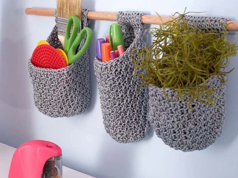 Small thread crochet baskets hanging from a wooden dowel